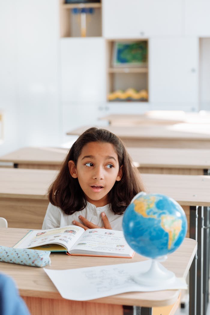 Crafting Captivating Headlines: Your awesome post title goes here A young girl in a classroom studies a globe, learning geography with an open book.